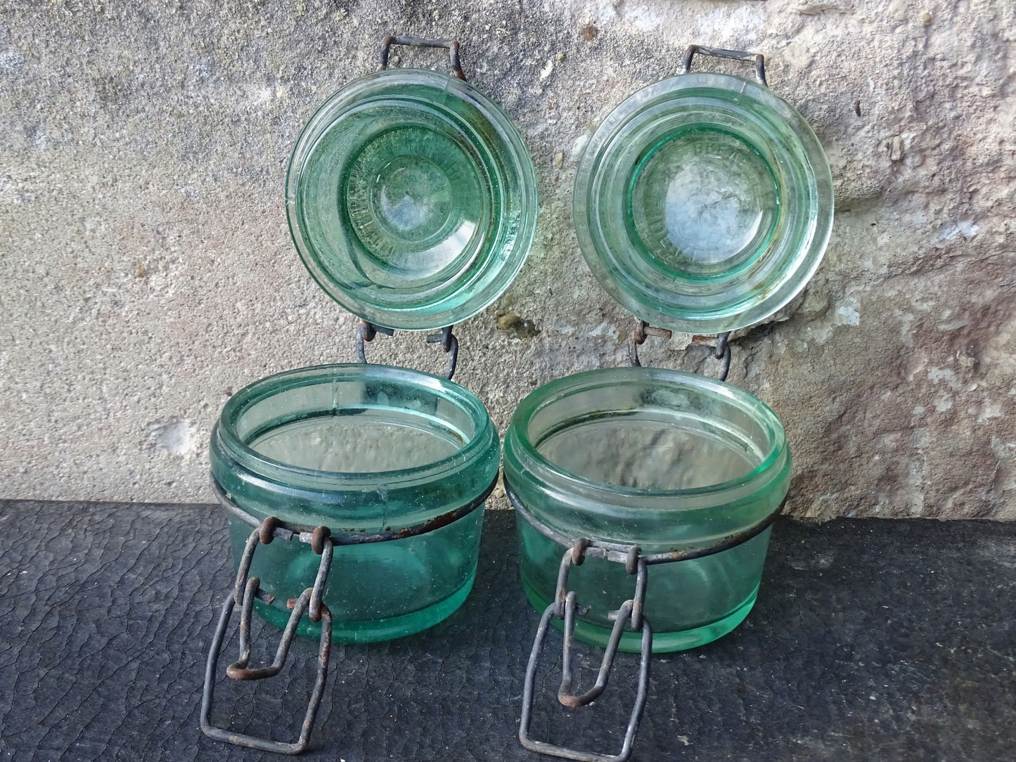 Pair of French vintage green glass preserving jars by L'Ideale. They have thick glass, embossed with the maker's name on top and original metal fasteners with a naturally aged finish. 