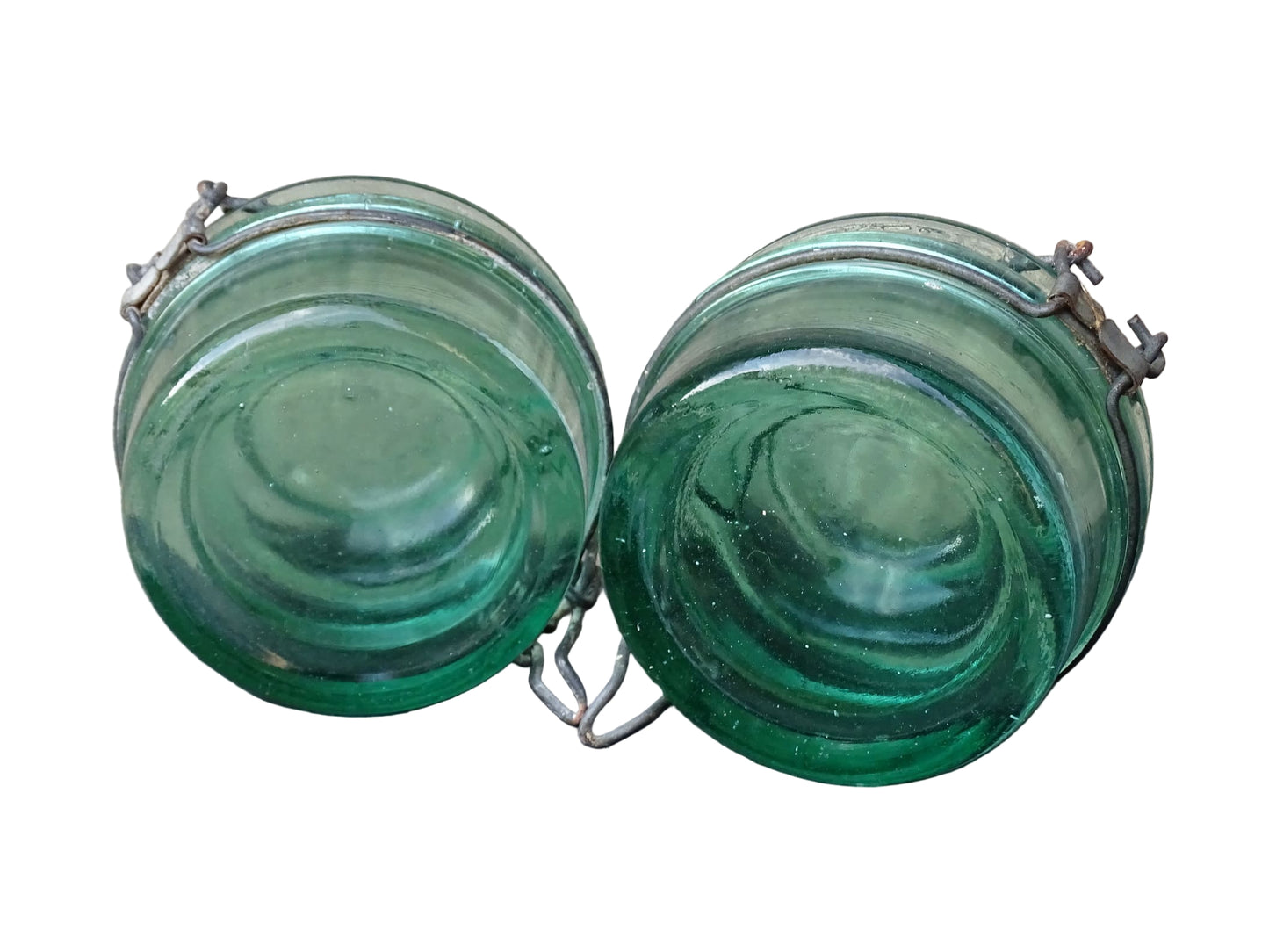 Pair of large French vintage green glass preserving jars by L'Ideale. They feature thick green glass, embossed detailing, and old metal clasps with a naturally aged finish. 