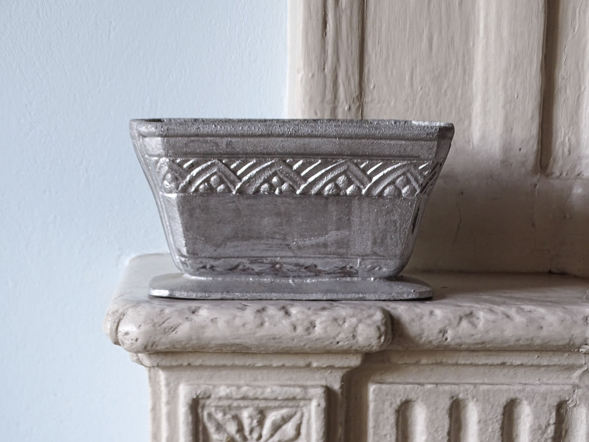 French antique cast iron planter in silver, pictured on a country house fireplace