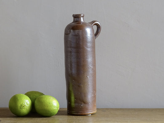 Antique salt glazed stoneware bottle, with a raised lion medallion on the shoulder and a loop handle. Bottle with textured surface and deep brown glaze. 