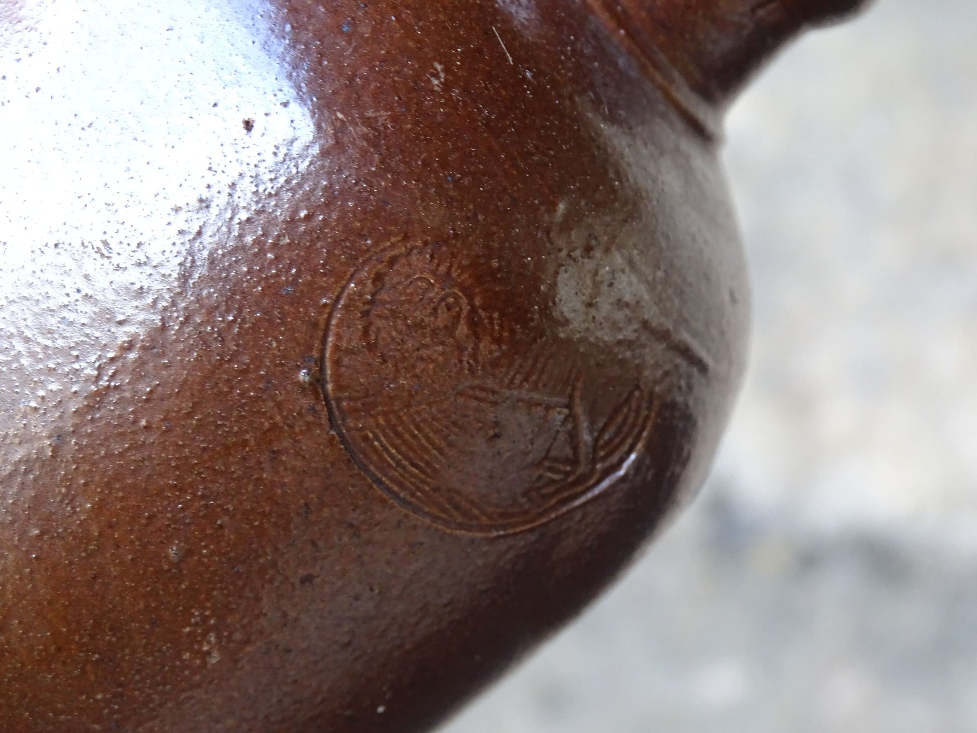 Antique salt glazed stoneware bottle, with a raised lion medallion on the shoulder and a loop handle. Bottle with textured surface and deep brown glaze. 