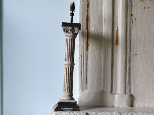 Vintage table lamp with Corinthian column base, pictured on a country house fireplace next to a pale blue wall