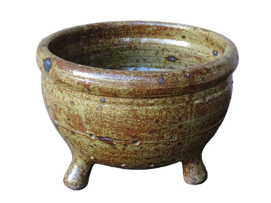 Rustic French vintage ceramic colander, stoneware berry strainer with a speckled glaze. It has a mix of warm earthy browns and olive tones, with darker fleck. It stands on three small feet and has a round form and softly curved rim.