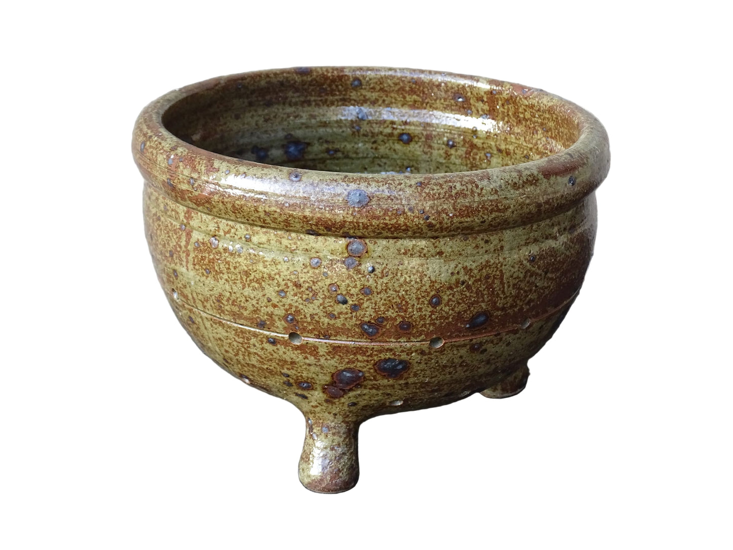 Rustic French vintage ceramic colander, stoneware berry strainer with a speckled glaze. It has a mix of warm earthy browns and olive tones, with darker fleck. It stands on three small feet and has a round form and softly curved rim.