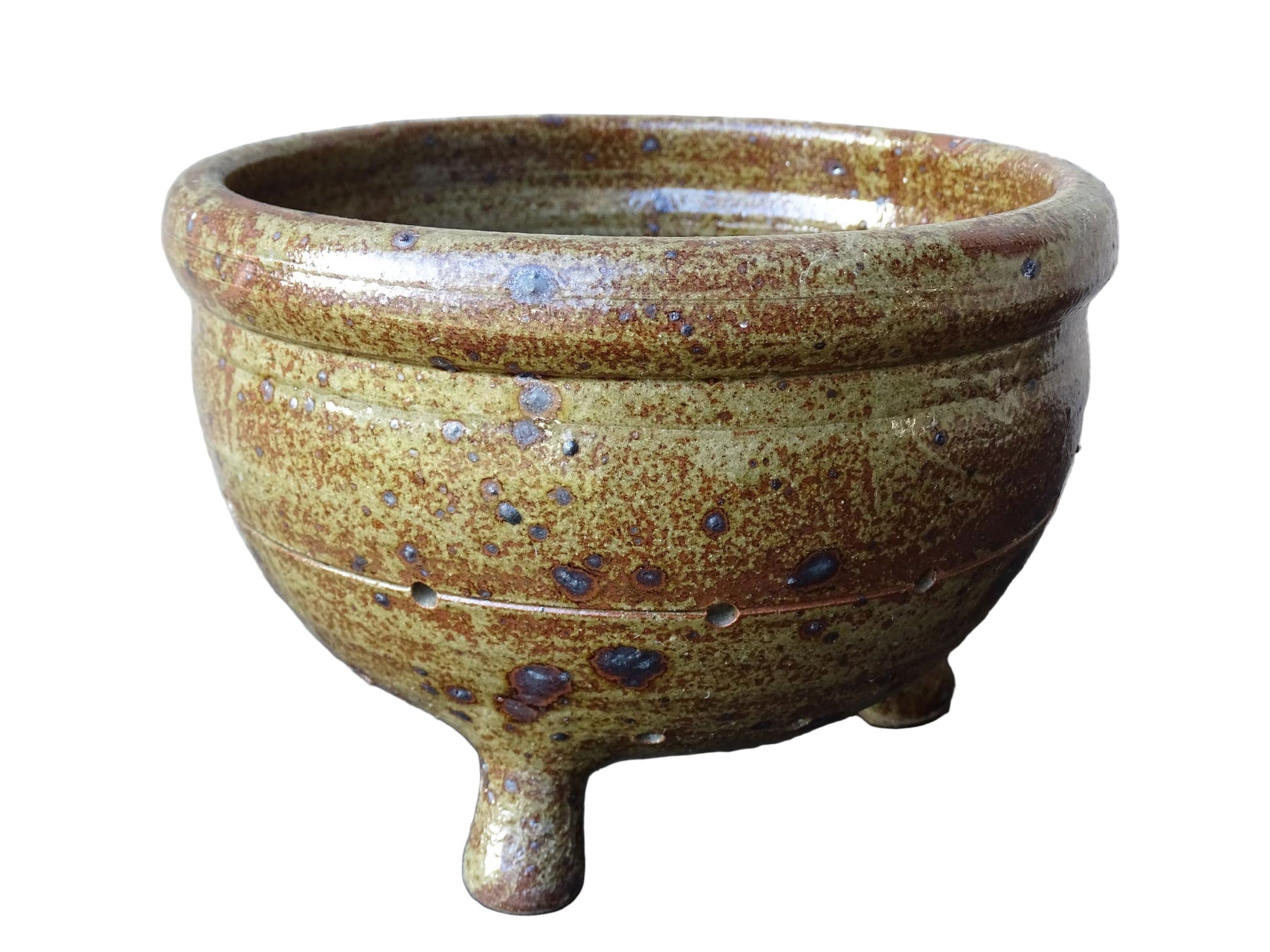 Rustic French vintage ceramic colander, stoneware berry strainer with a speckled glaze. It has a mix of warm earthy browns and olive tones, with darker fleck. It stands on three small feet and has a round form and softly curved rim.