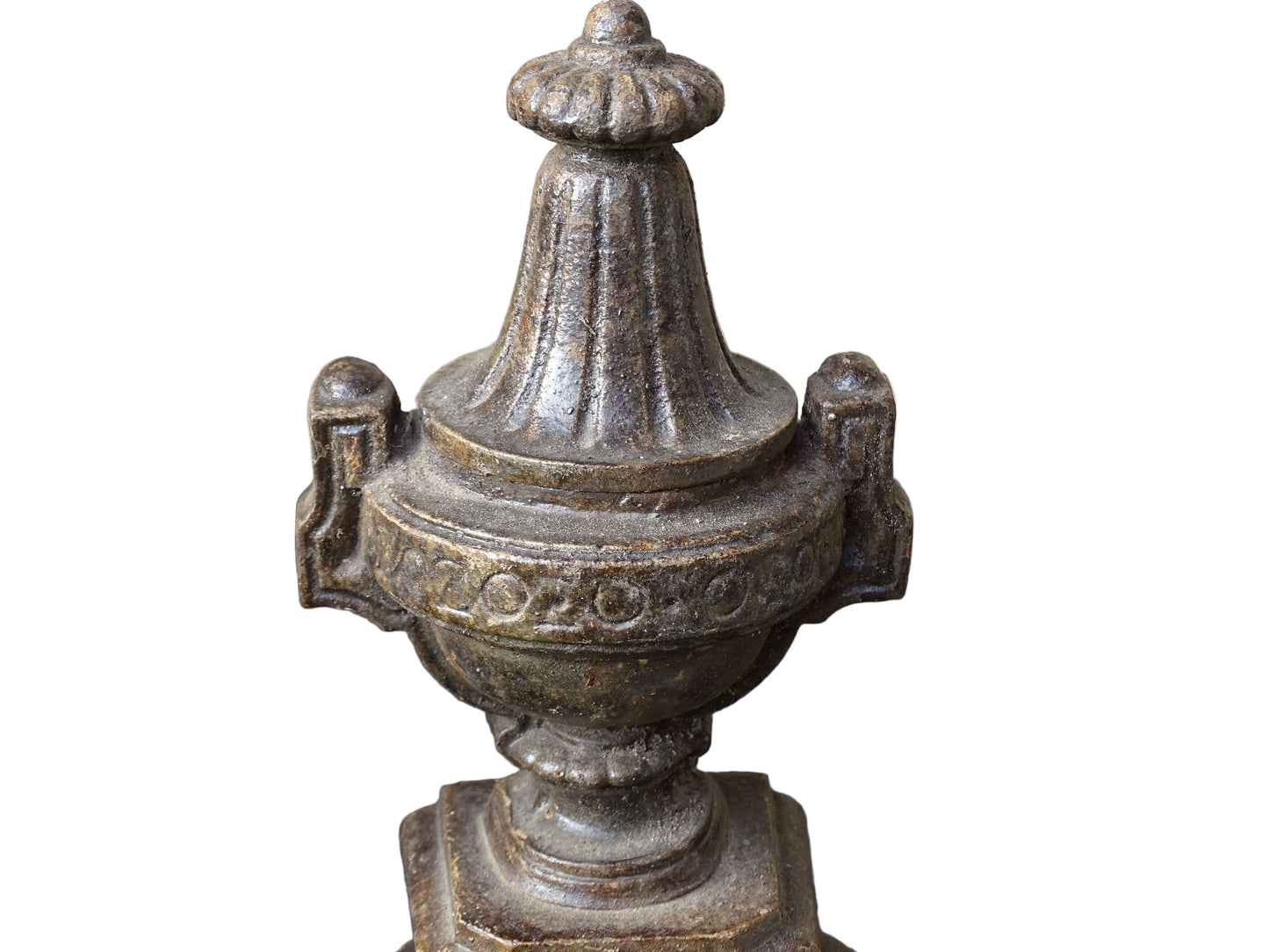 Pair of French antique cast iron andirons or fire dogs with a classical style. Each andiron is topped with an urn-shaped finial, accented by moulded details and a fluted form that evokes neoclassical architectural design. The bases are decorated with scrolling motifs and small medallions. 