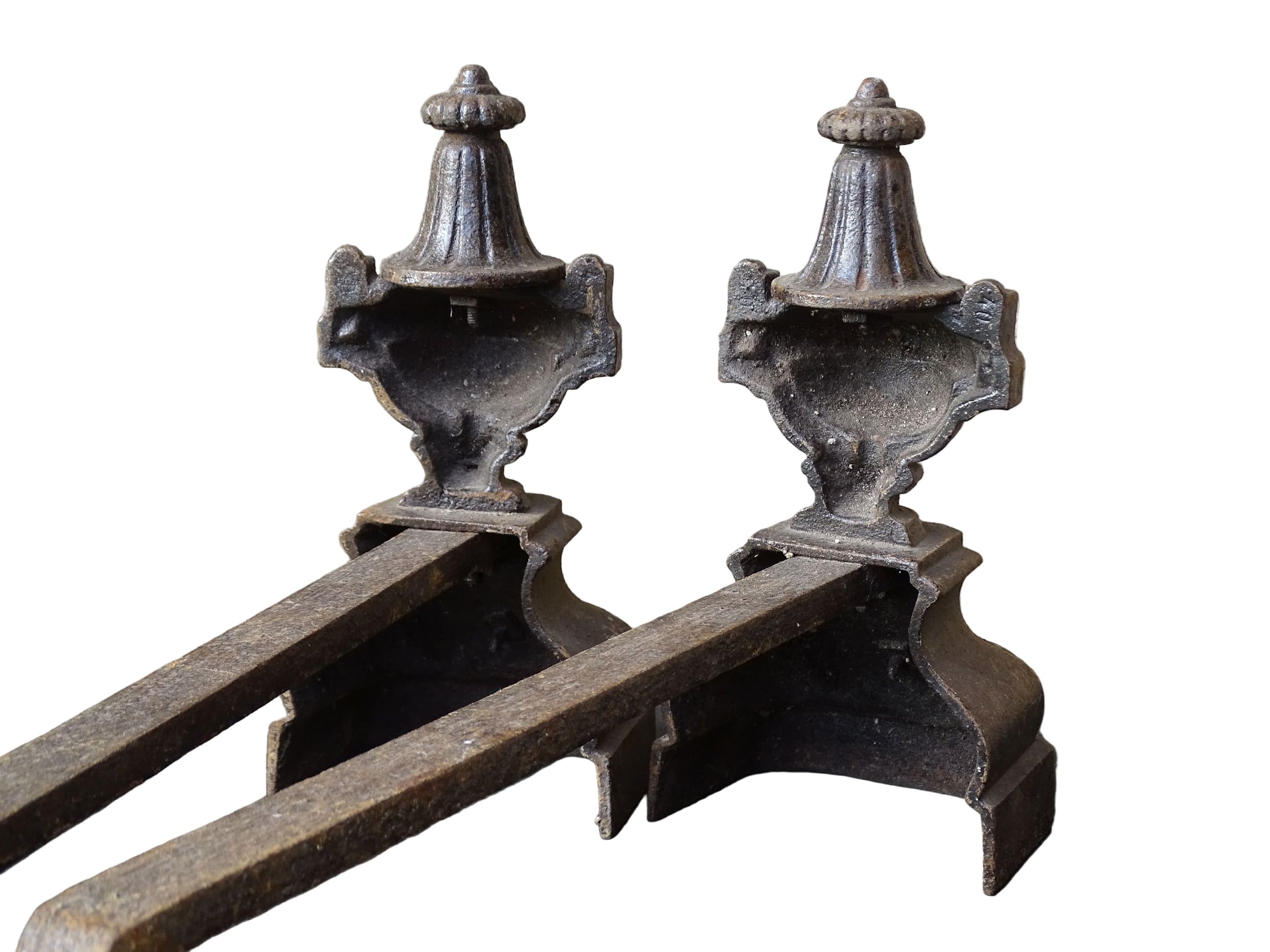 Pair of French antique cast iron andirons or fire dogs with a classical style. Each andiron is topped with an urn-shaped finial, accented by moulded details and a fluted form that evokes neoclassical architectural design. The bases are decorated with scrolling motifs and small medallions. 