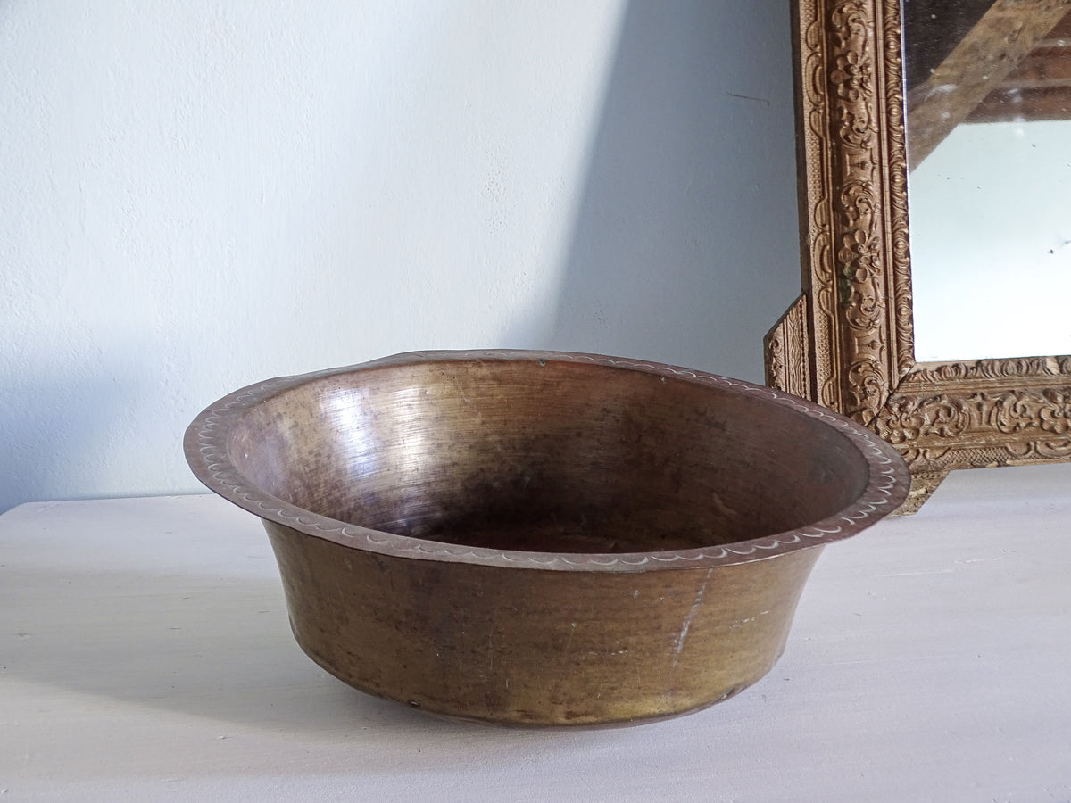 Antique copper basin pictured next to a gold mirror
