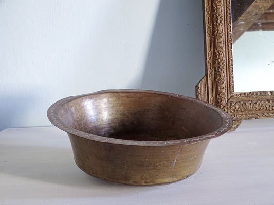 Antique copper basin pictured next to a gold mirror