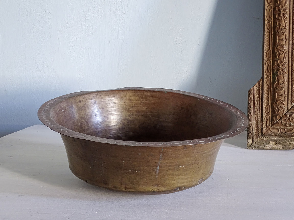 French antique copper bowl pictured next to an ornate gold mirror