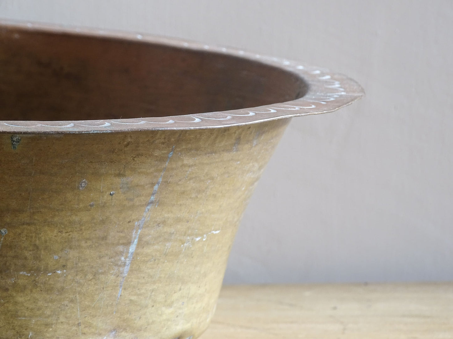 A  timeworn French antique copper bowl with hammered detailing to the rim and a rounded base. This copper bowl has a beautiful, aged patina. 