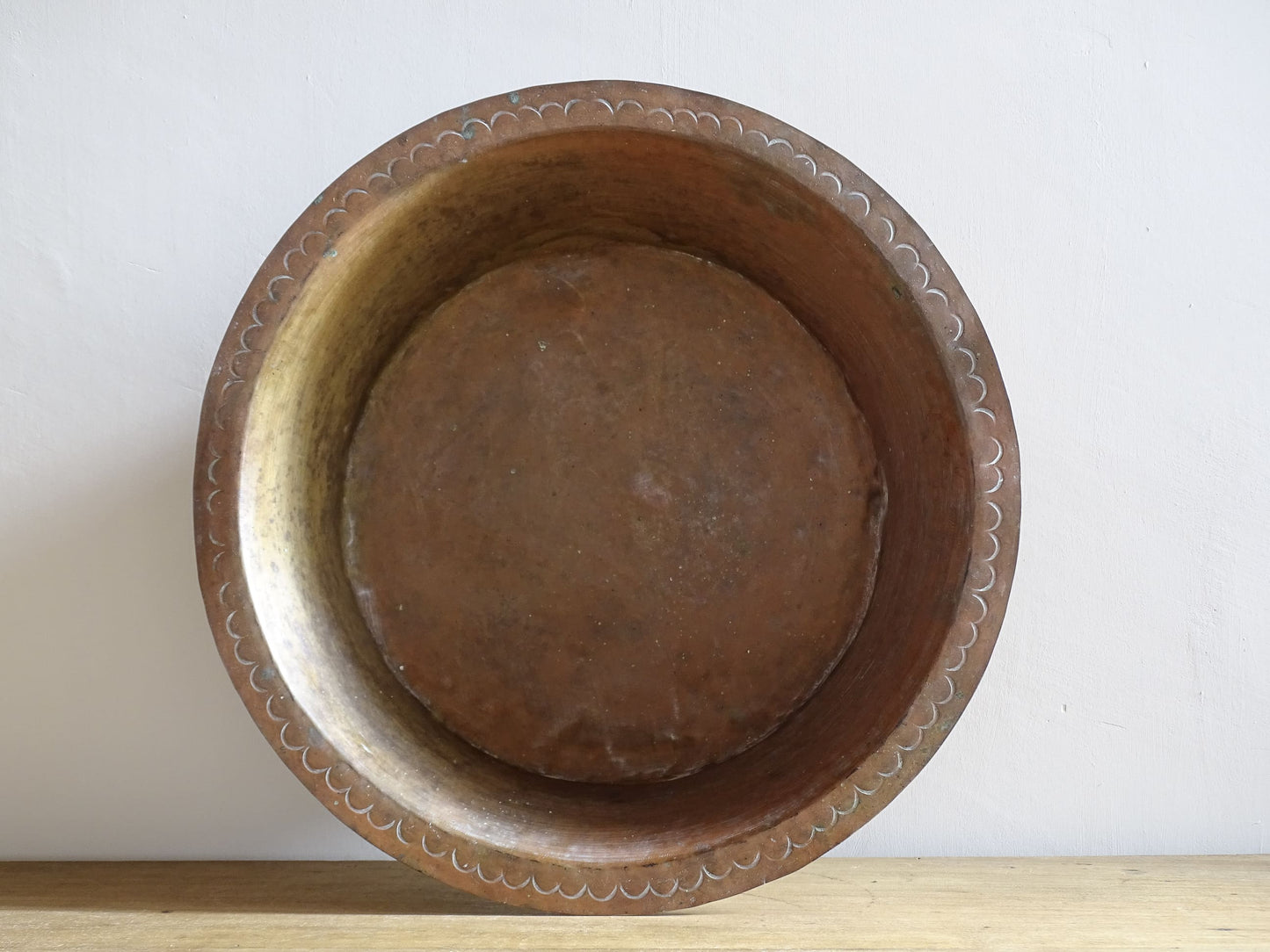 A  timeworn French antique copper bowl with hammered detailing to the rim and a rounded base. This copper bowl has a beautiful, aged patina. 