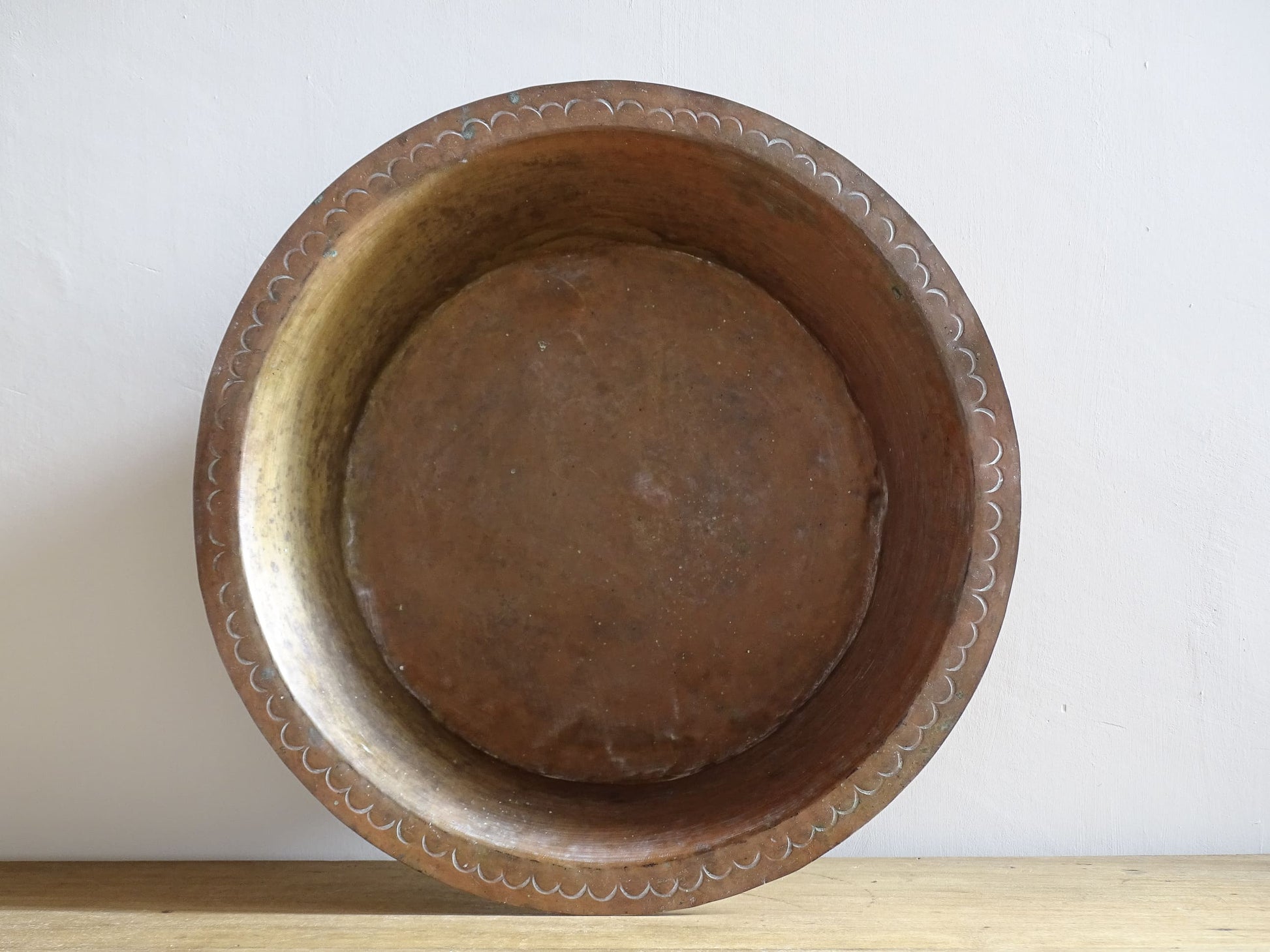 A  timeworn French antique copper bowl with hammered detailing to the rim and a rounded base. This copper bowl has a beautiful, aged patina. 
