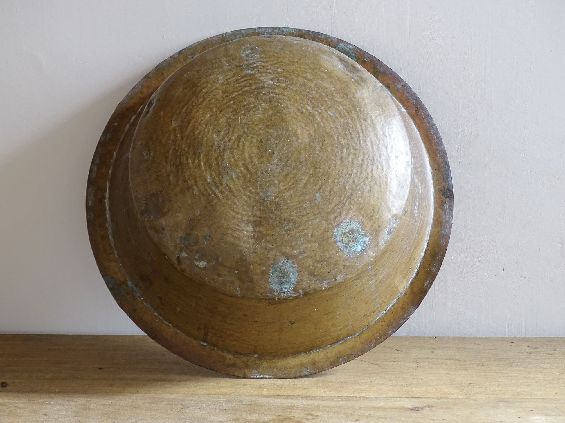 A  timeworn French antique copper bowl with hammered detailing to the rim and a rounded base. This copper bowl has a beautiful, aged patina. 