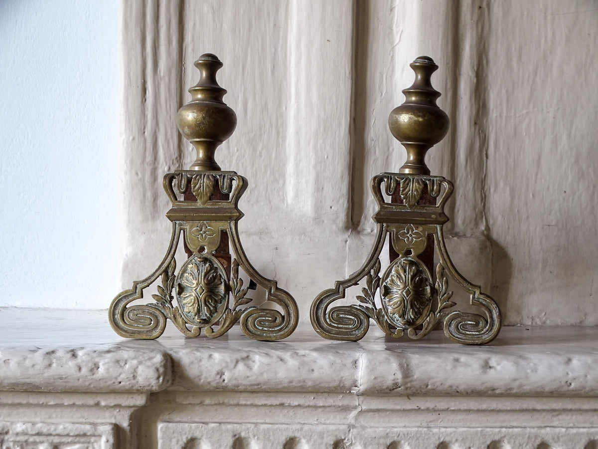 French antique brass andirons or firedogs with scrolling details, pictured on a country house fireplace