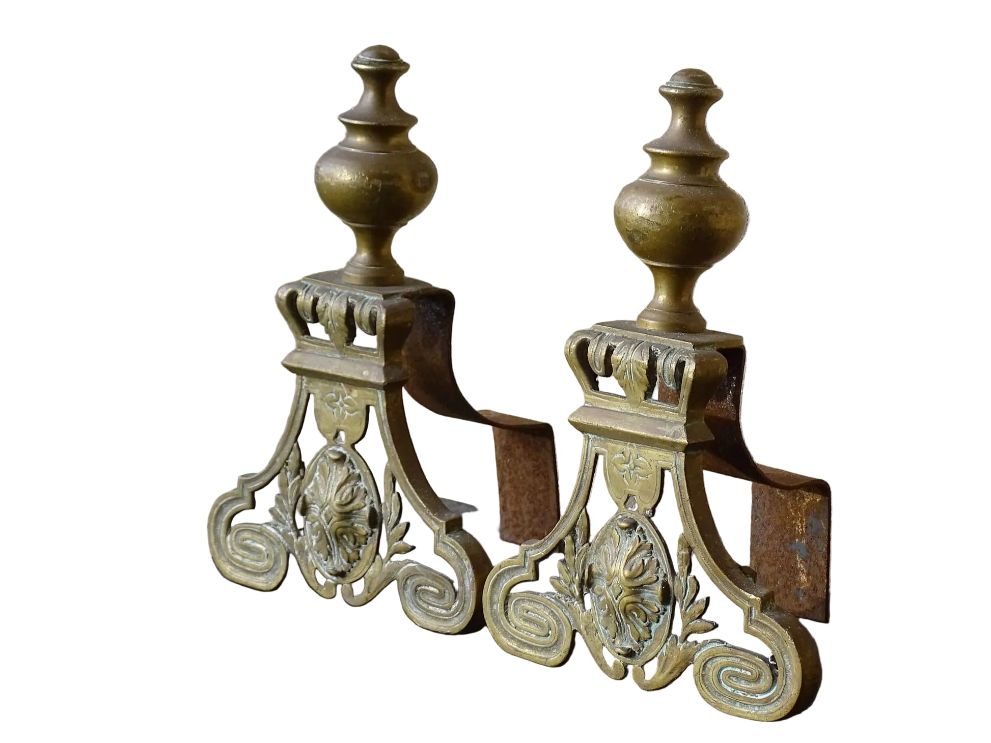Pair of French antique brass andirons or fire dogs in a Louis XVI revival style. Each andiron is topped with a turned baluster finial. The pierced front plates display an ornate composition of acanthus leaves, scrollwork, and a central oval cartouche framed by laurel branches, typical of neoclassical design.