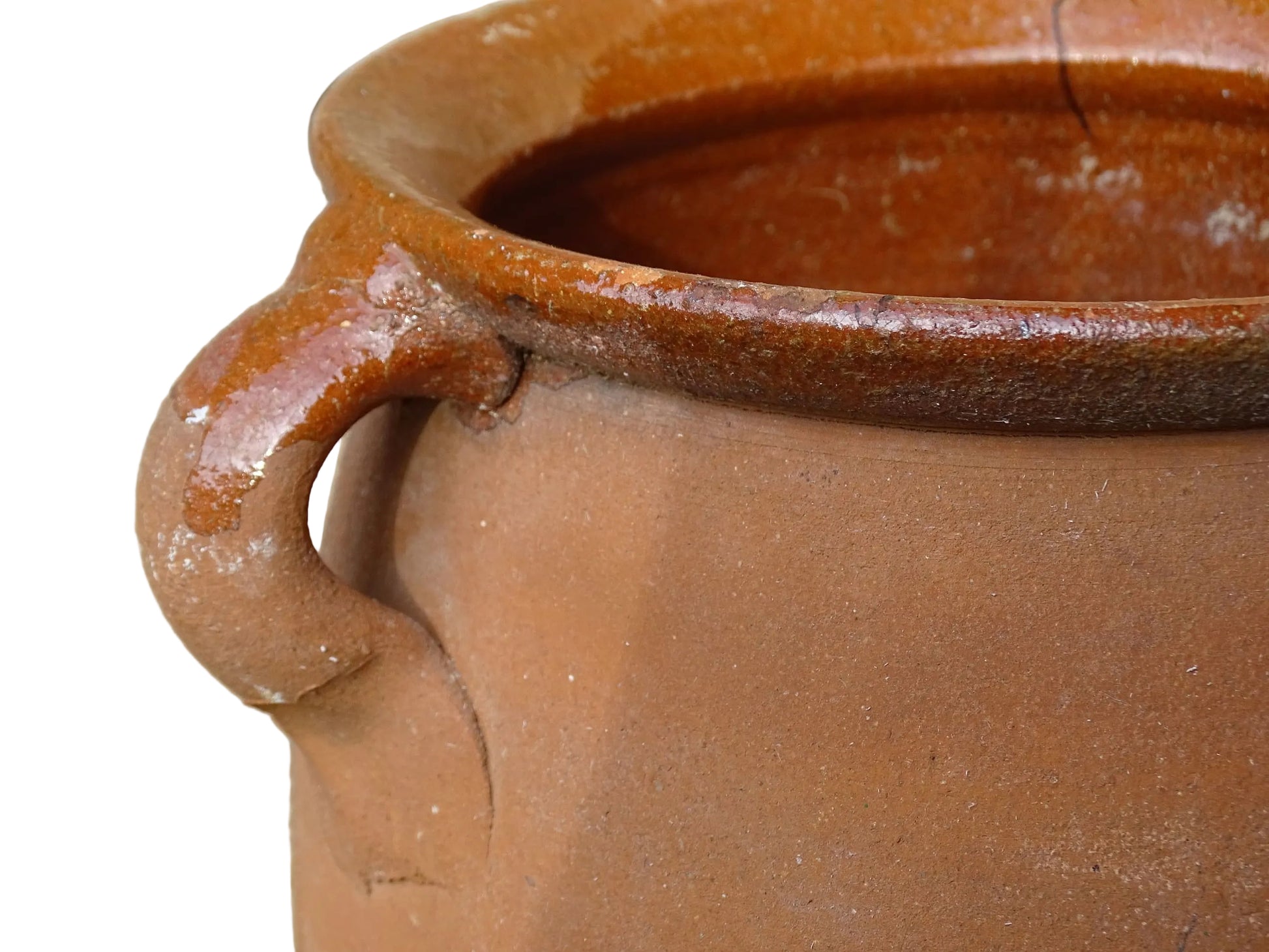 French vintage terracotta pot with orange glaze interior and drip glaze around the sides. Earthenware confit jar with two handles and a curved base.