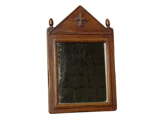 French antique wooden mirror with fleur de lis motif. The wood mirror is topped by a pediment with two turned finials.