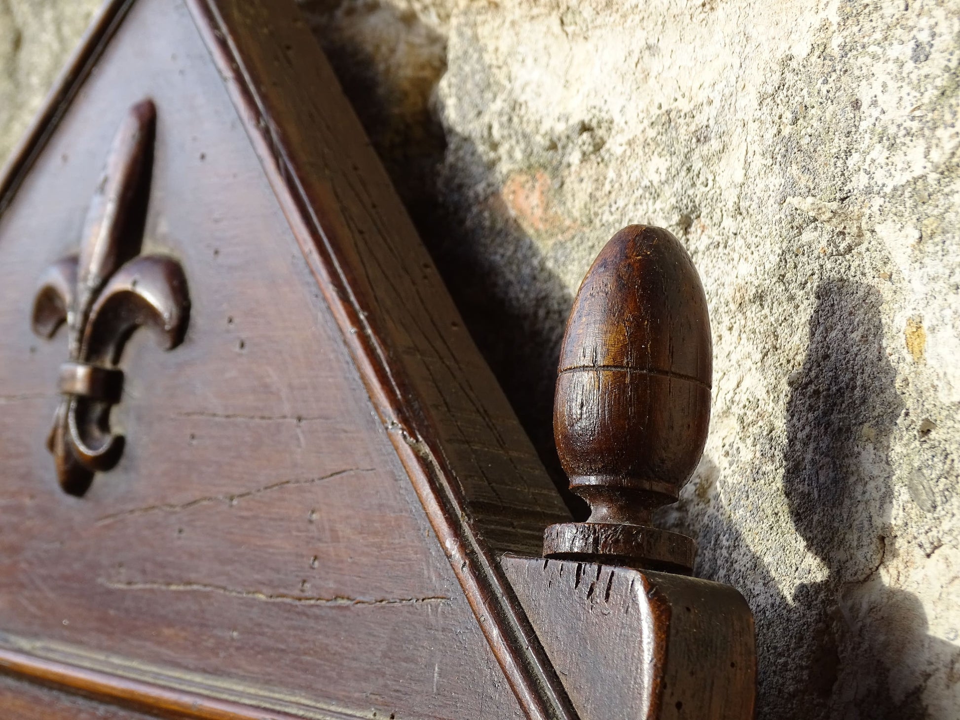 French antique wooden mirror with fleur de lis motif. The wood mirror is topped by a pediment with two turned finials.