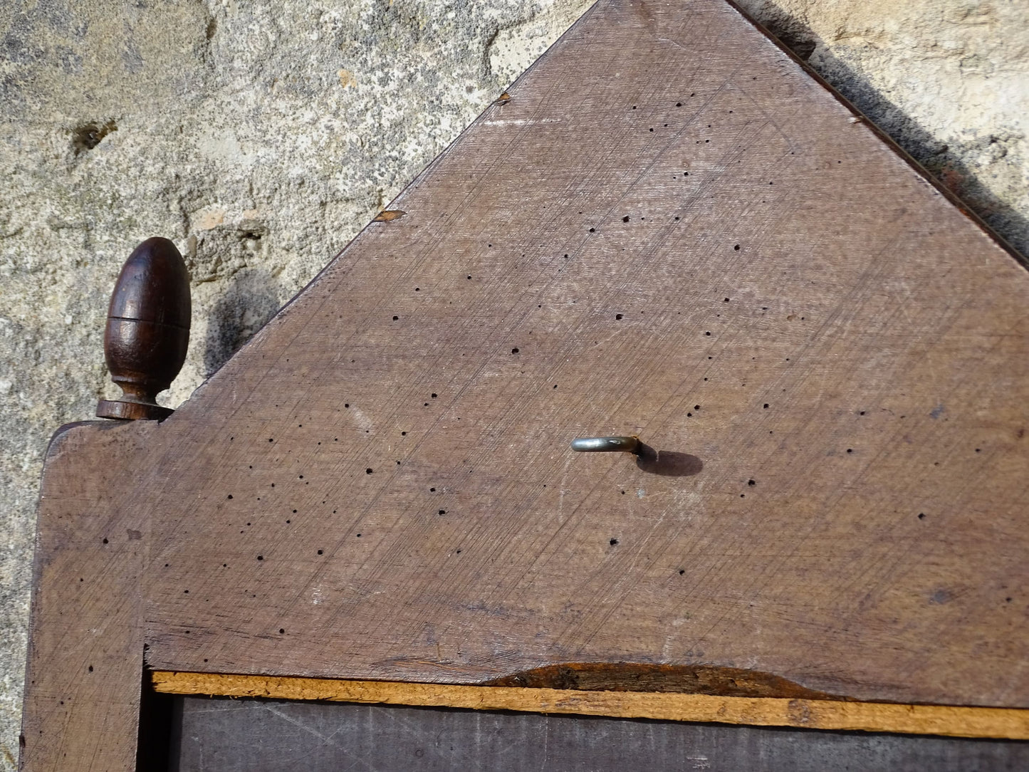 French antique wooden mirror with fleur de lis motif. The wood mirror is topped by a pediment with two turned finials.