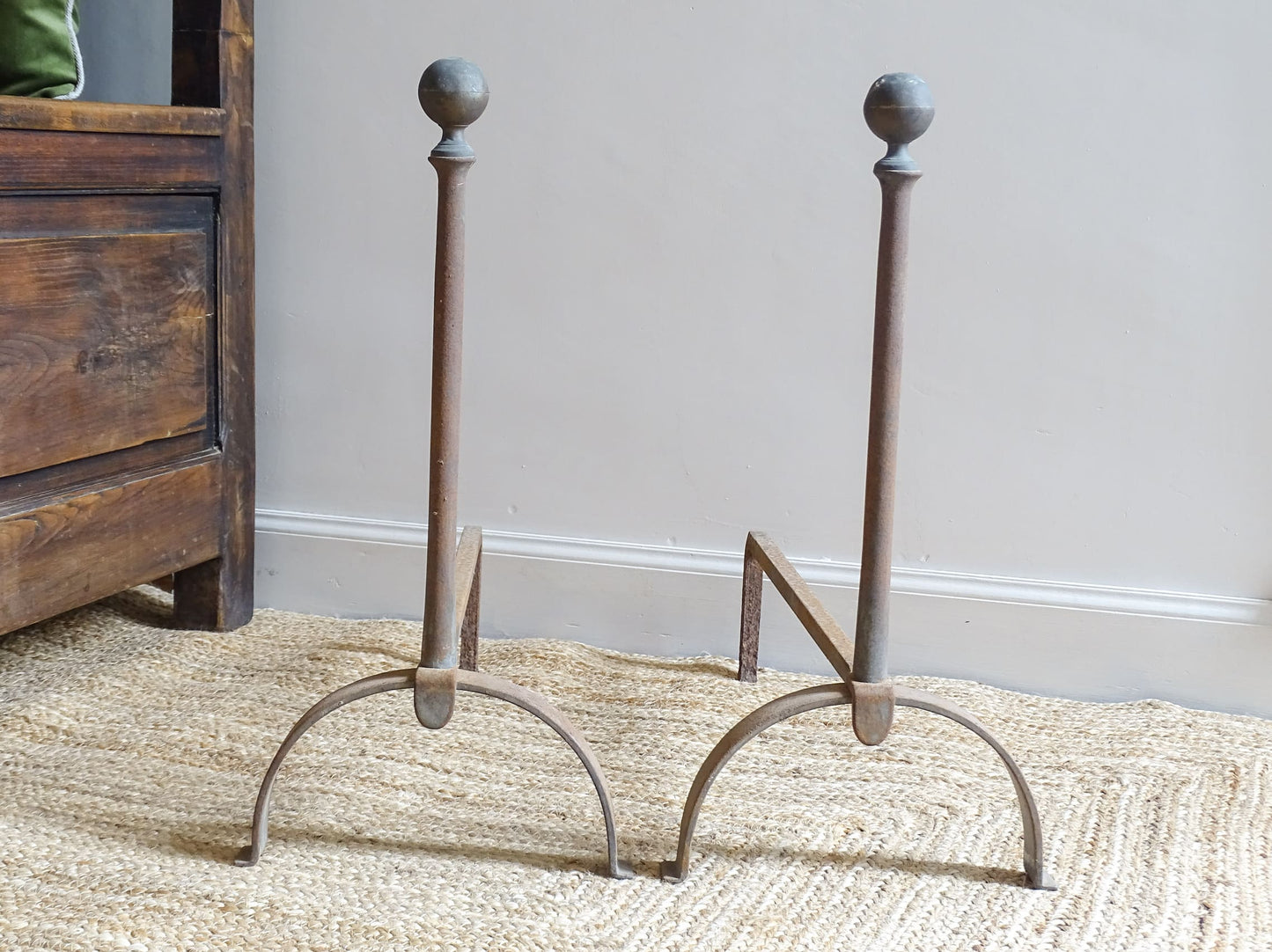 Pair of French antique cast iron andirons or fire dogs, dating to the 19th century. They are rustically aged. These antique fire dogs have globe finials and have beautifully simple farmhouse aesthetic.