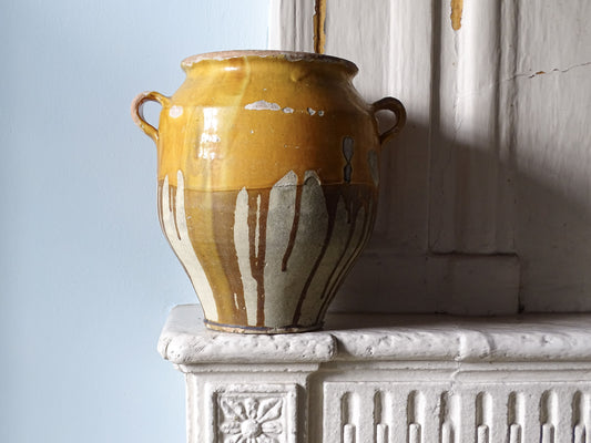 Large French antique confit pot with yellow glaze on a country house fireplace