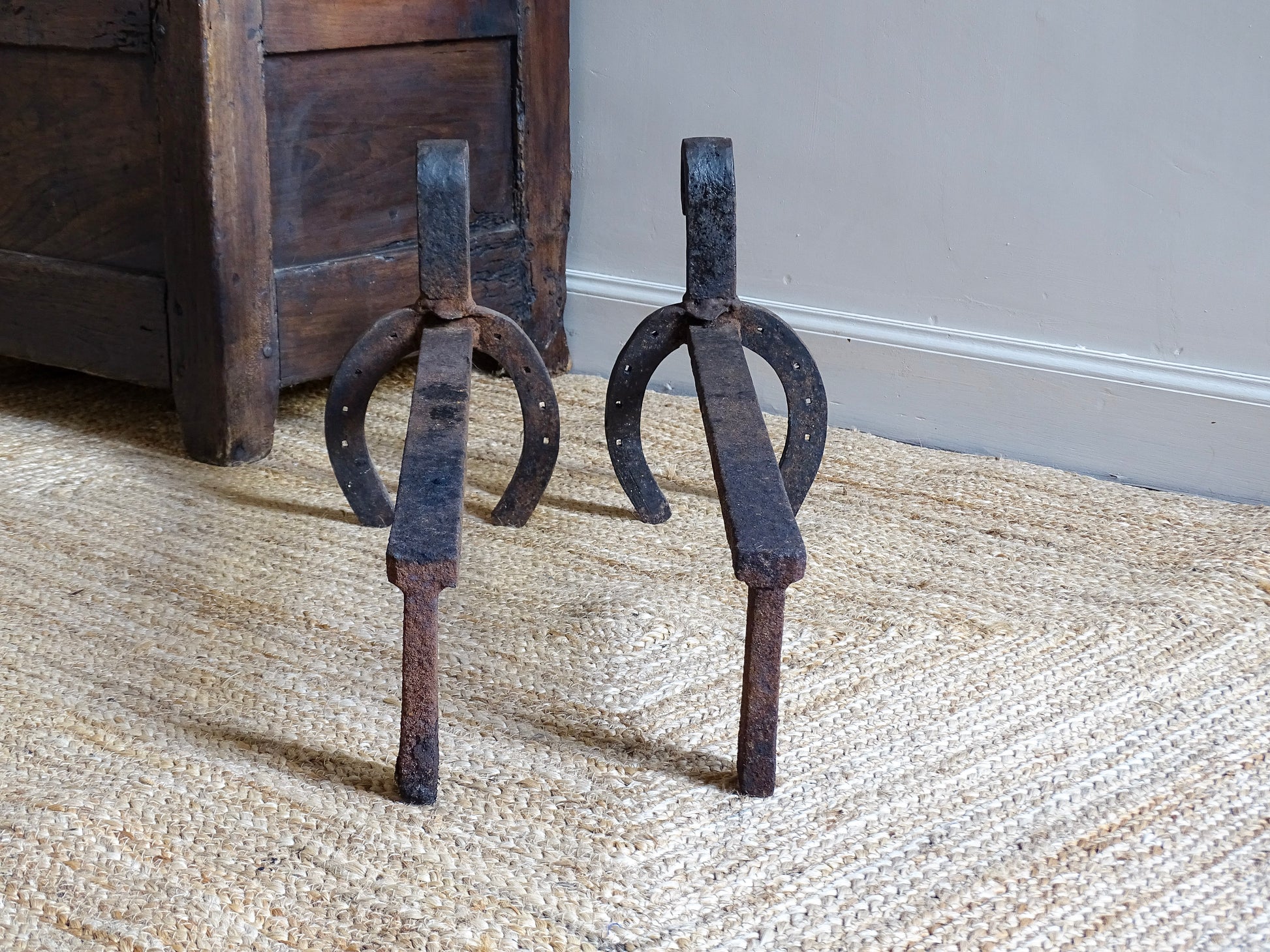  pair of French antique wrought iron andirons or fire dogs, date to the 19th century. They incorporate hand-forged horseshoes, with square-punched nail holes and substantial rear supports. A rustic, agricultural design with authentic forge marks throughout.