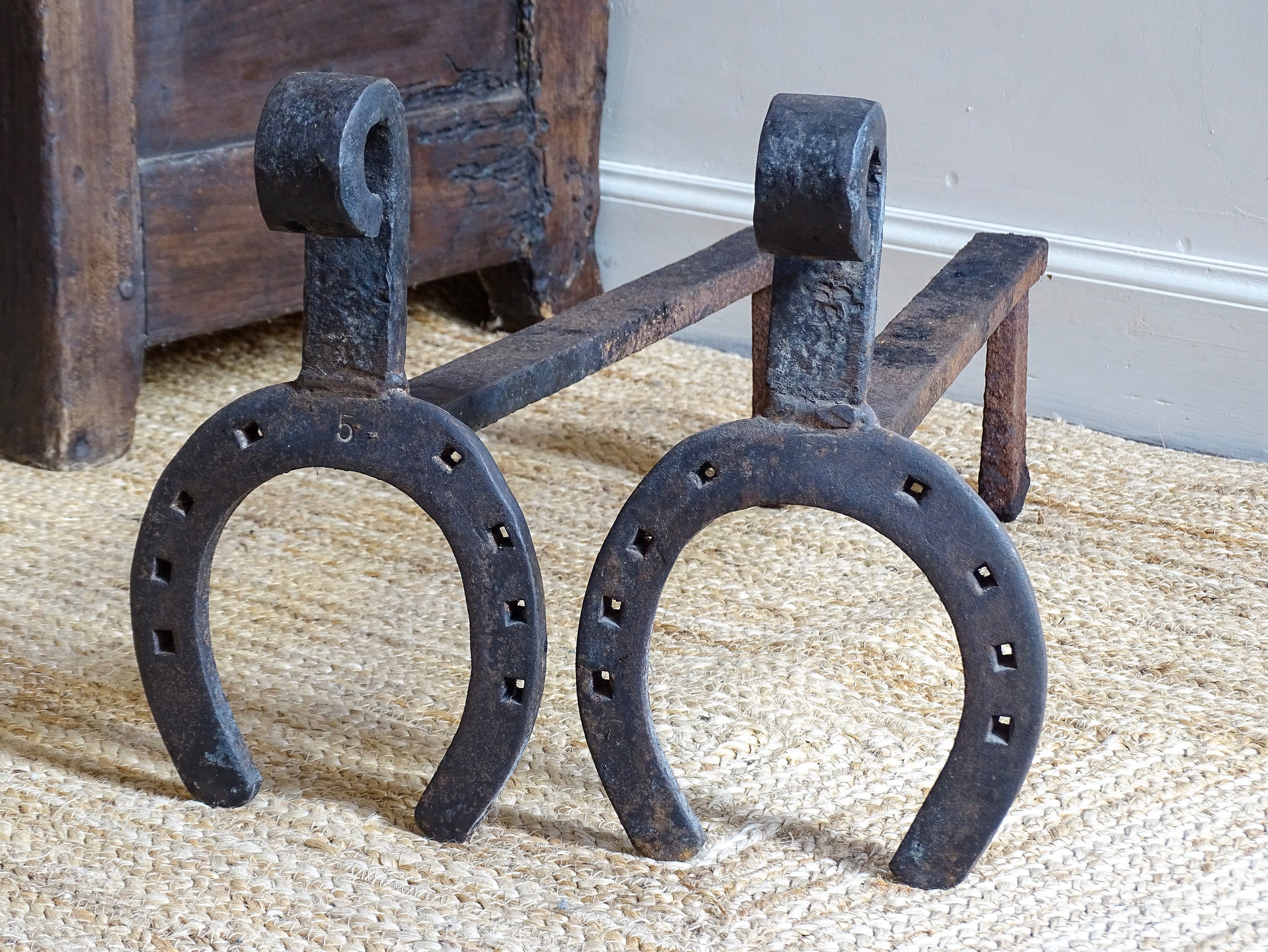  pair of French antique wrought iron andirons or fire dogs, date to the 19th century. They incorporate hand-forged horseshoes, with square-punched nail holes and substantial rear supports. A rustic, agricultural design with authentic forge marks throughout.