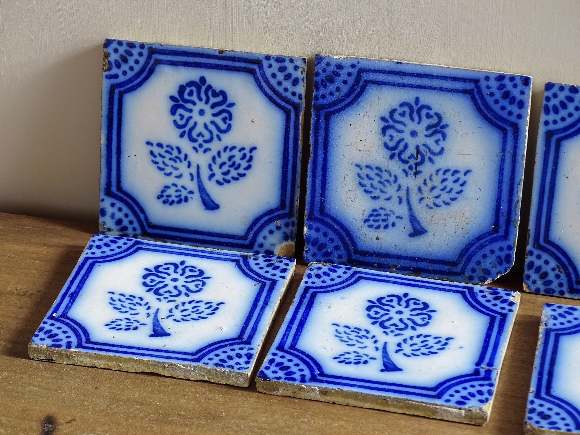 A set of eight French antique Desvres faience tiles in blue &amp; white. These transfer printed, earthenware tiles were manufactured in the late 1900's in Desvres, Northern France. Six of the tiles are back-stamped. They are beautifully transfer printed in cobalt blue. A floral sprig sits in the centre of the cartouche framing.