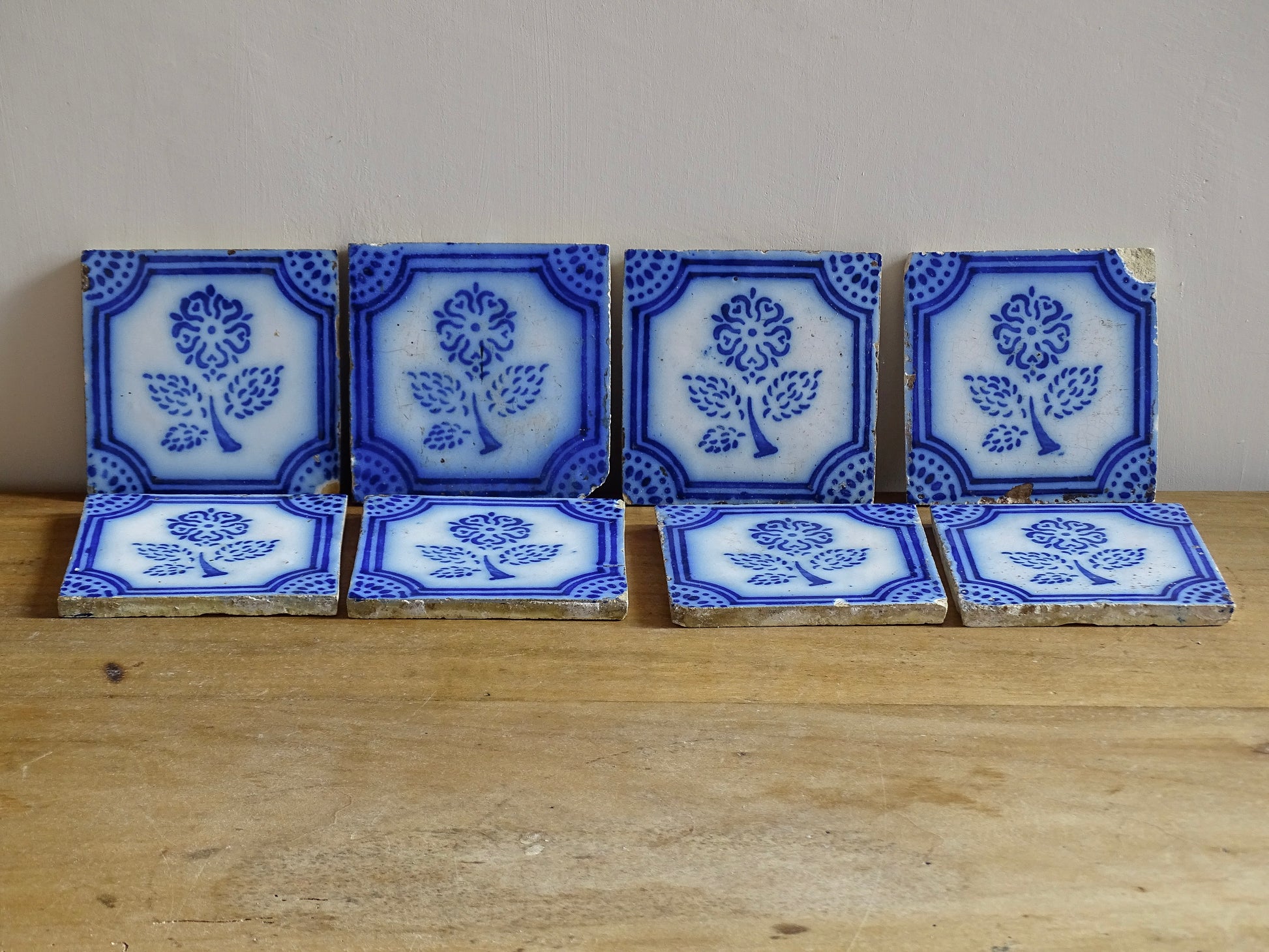 A set of eight French antique Desvres faience tiles in blue &amp; white. These transfer printed, earthenware tiles were manufactured in the late 1900's in Desvres, Northern France. Six of the tiles are back-stamped. They are beautifully transfer printed in cobalt blue. A floral sprig sits in the centre of the cartouche framing.