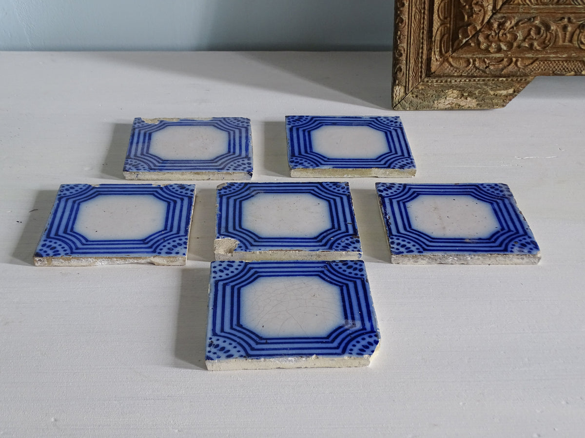 Set of six French antique earthenware tiles with blue and white geometric pattern by Desvres, pictured next to an ornate gold mirror