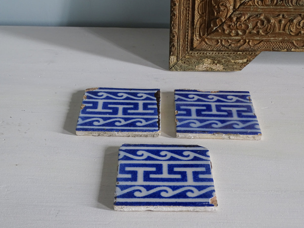 Set of 3 French antique earthenware tiles with Greek key motifs in a blue and white glaze by Desvres, pictured next to an ornate gold frame