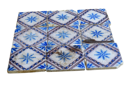 A set of nine French antique Desvres faience tiles in blue &amp; white. These transfer printed, earthenware tiles were manufactured in the late 1900's in Desvres, Northern France. The tiles are back-stamped. Each tile is decorated in cobalt blue on a white tin-glazed ground, centred with a stylised starburst motif and framed within a manganese-purple diamond border.