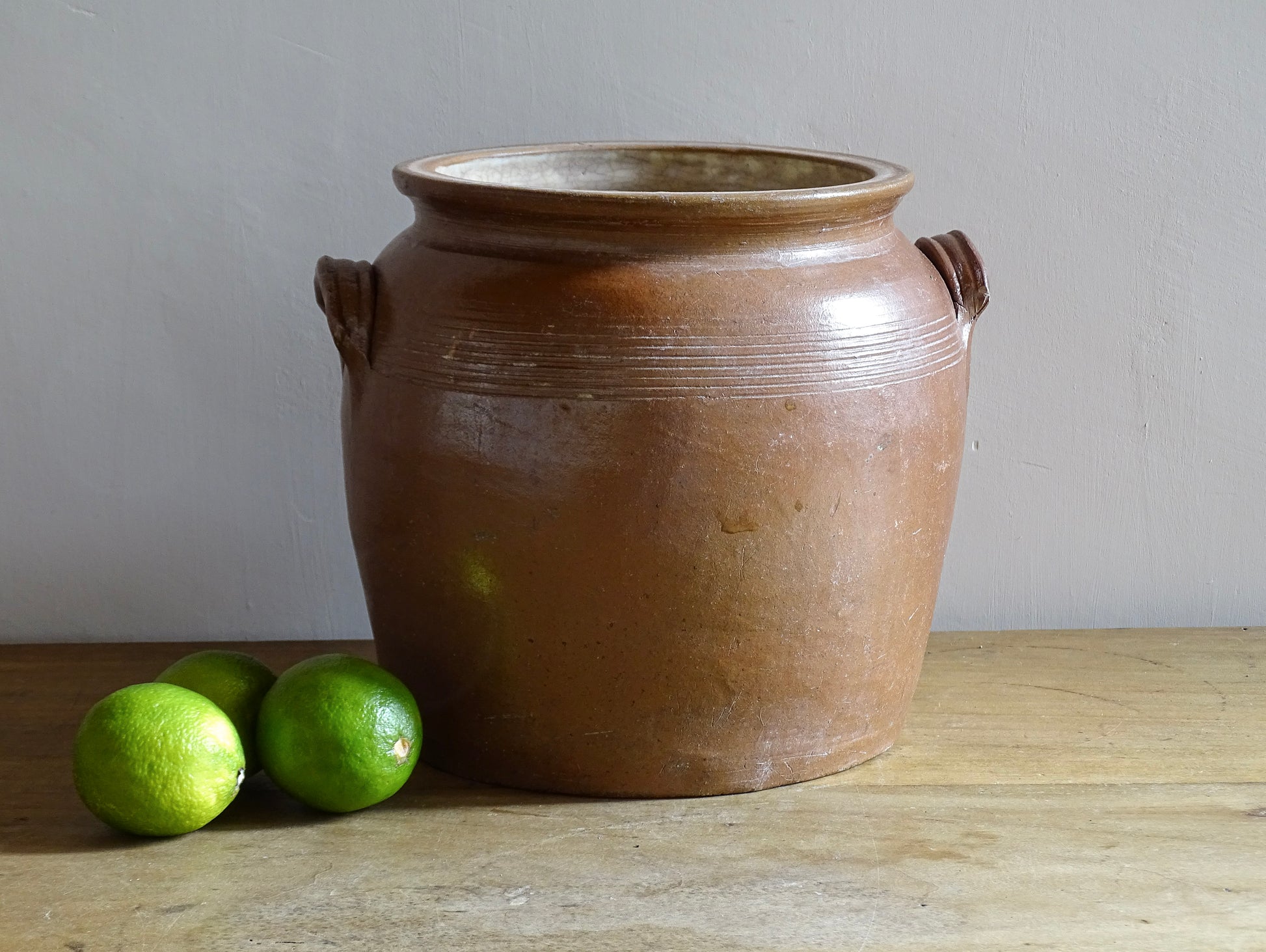A French antique stoneware confit pot with a brown glaze. This is a salt glazed pottery cache pot. It dates to the early 20th century and would look amazing as part of a rustic French farmhouse style home. 