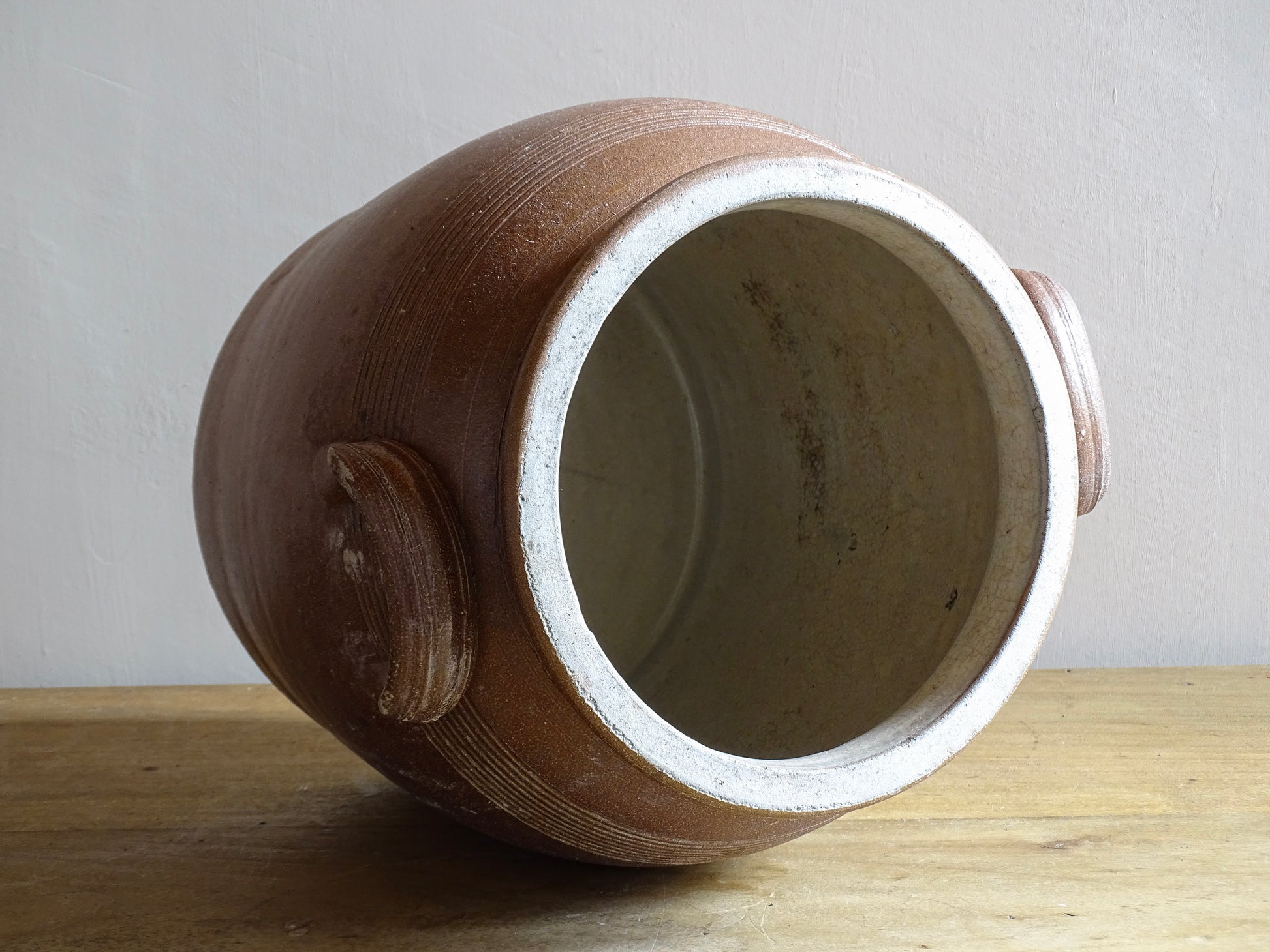 A French antique stoneware confit pot with a brown glaze. This is a salt glazed pottery cache pot. It dates to the early 20th century and would look amazing as part of a rustic French farmhouse style home. 