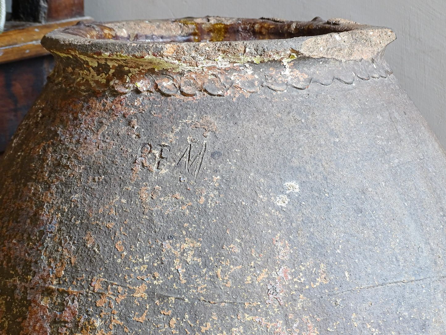 A large, early 19th century French antique terracotta pot, known as a ponne (salting pot), sourced in the Bordeaux region and likely Charentais in origin. This example has a beautifully rounded, generous form with a rolled rim. The surface is particularly special, showing layers of time, wear and historic pigment. Traces of faded blue and earthy tones remain across the body, creating a richly textured patina. 