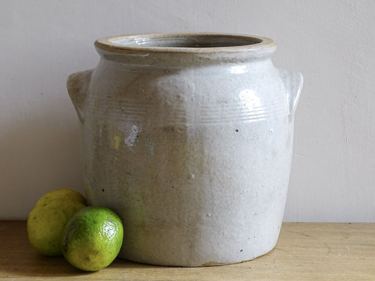 Antique stoneware jar or French confit pot with a beige glaze and two handles in a rustic country kitchen style.