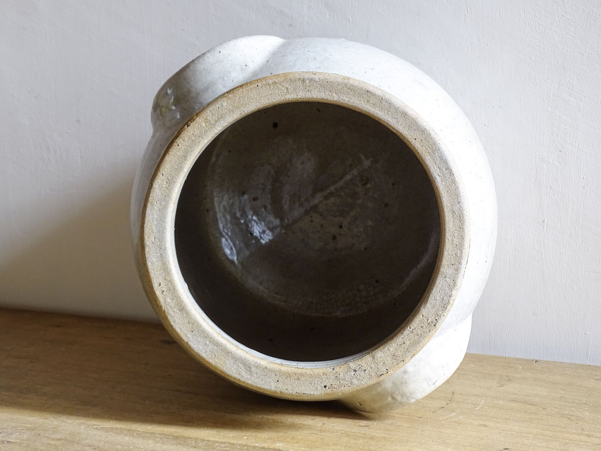 Inside view of an antique stoneware jar or French confit pot with a beige glaze and two handles in a rustic country kitchen style.