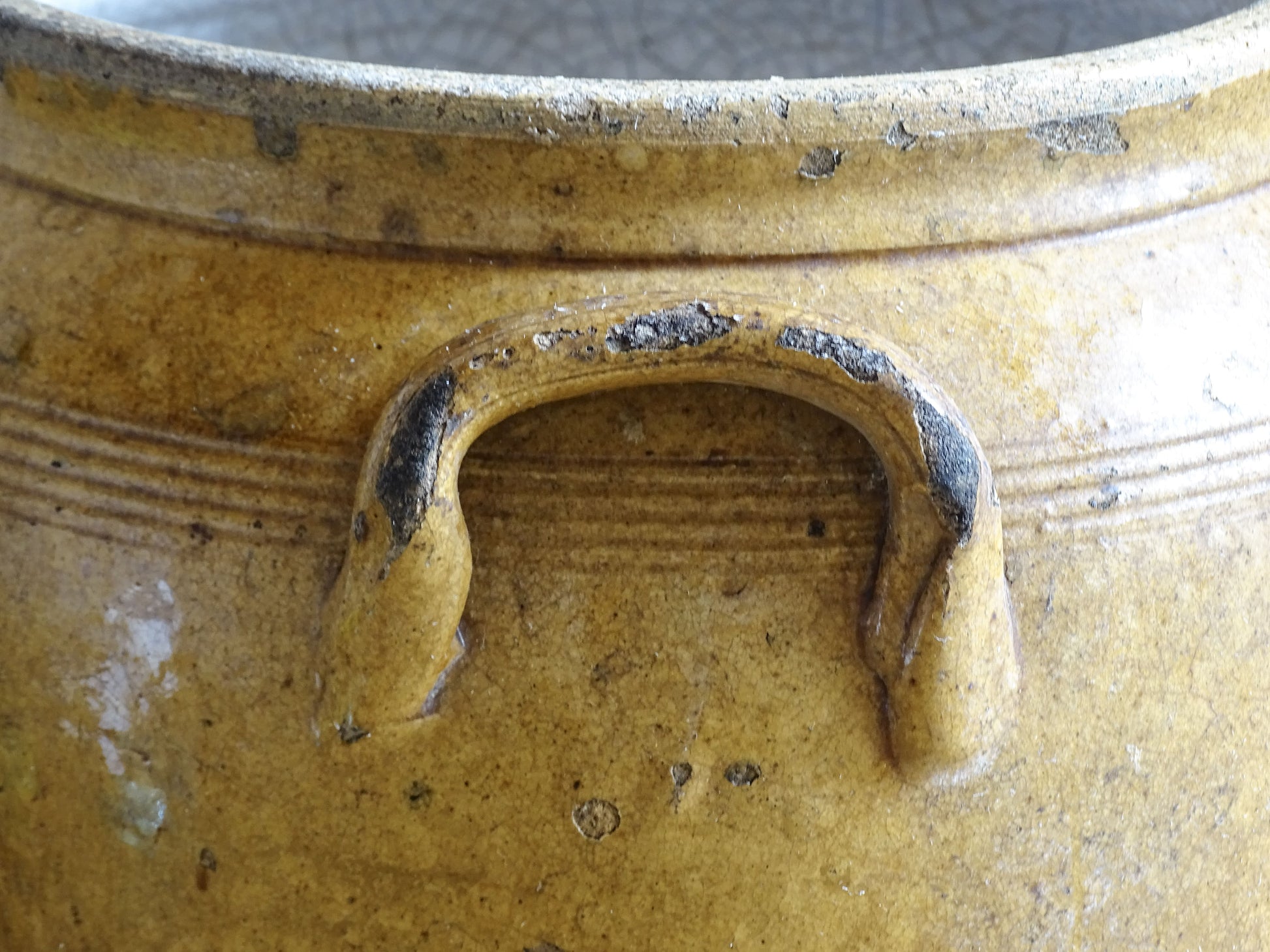 Close up of the handle of an antique stoneware pot with a brown glaze. French confit pot or preserving jar.