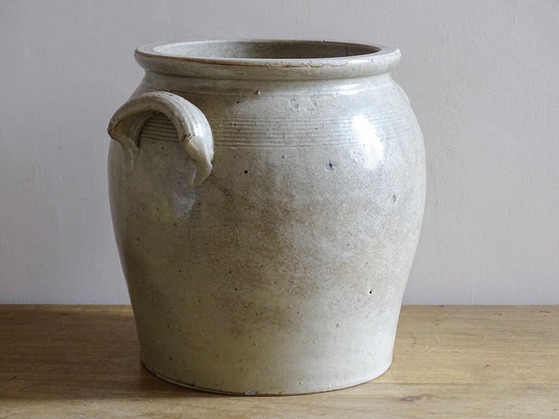 Side view of an antique ceramic jar with a beige glaze, a French confit pot