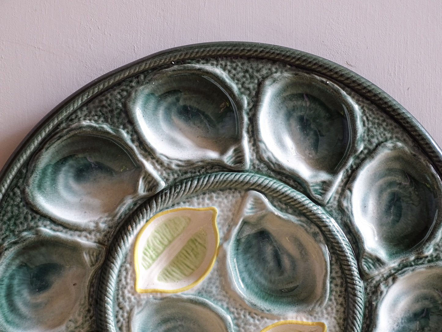 Green glazed St Clément oyster plate displaying sculpted shell forms around the rim.