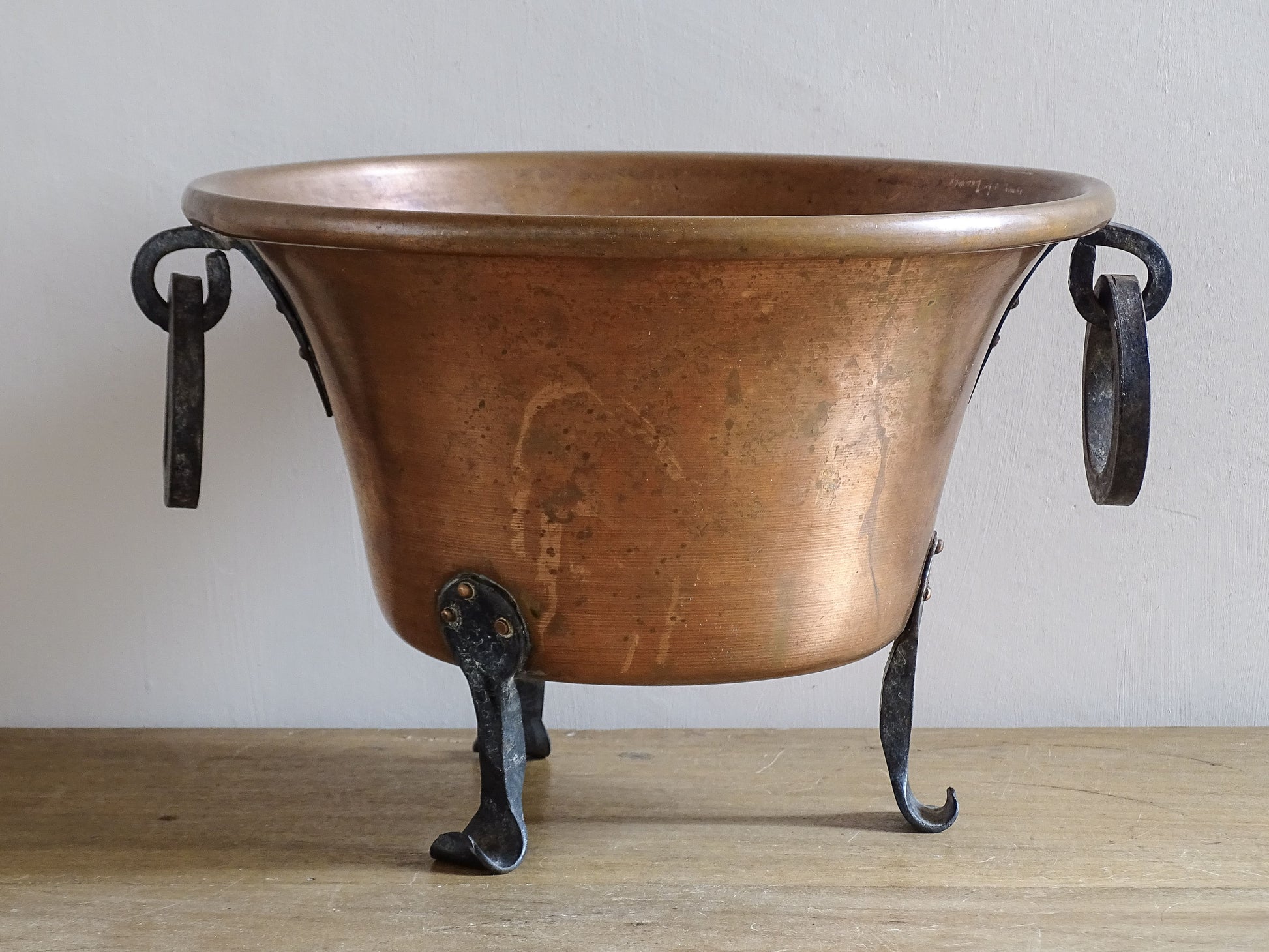 Mid-century French copper jardinière with dark wrought iron handles and scrolling tripod feet.