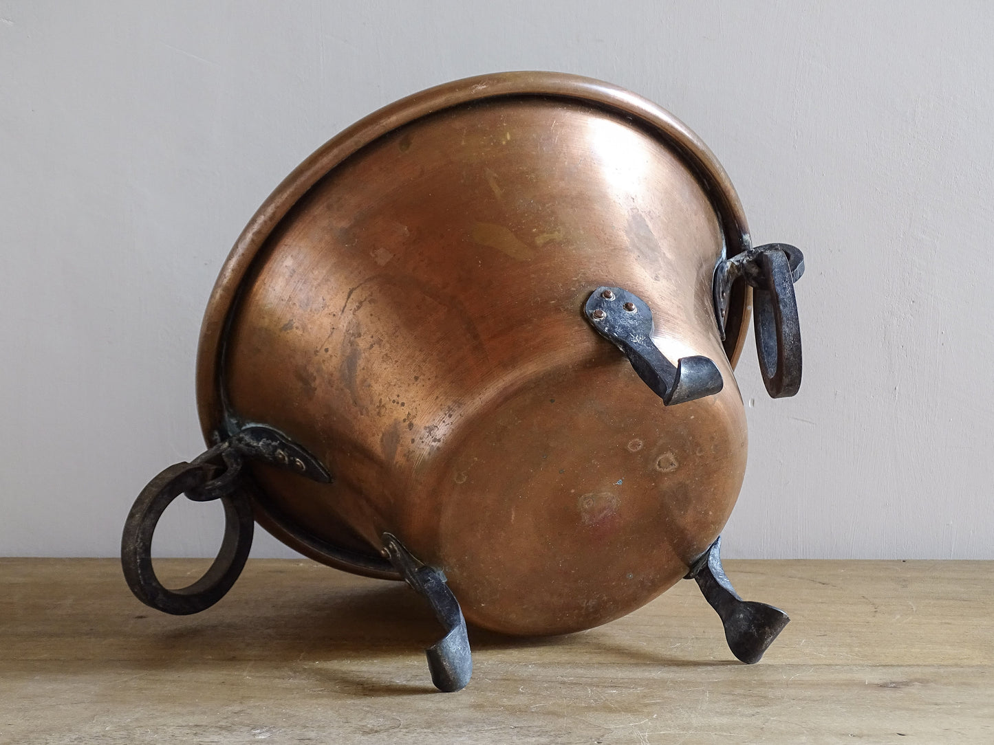 Underside of vintage copper planter showing riveted wrought iron feet and copper base.