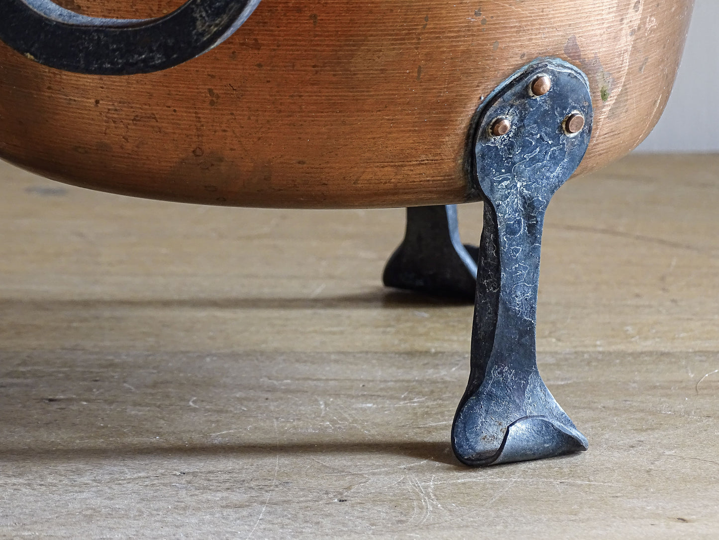 Close view of forged iron foot attached to a vintage copper jardinière.