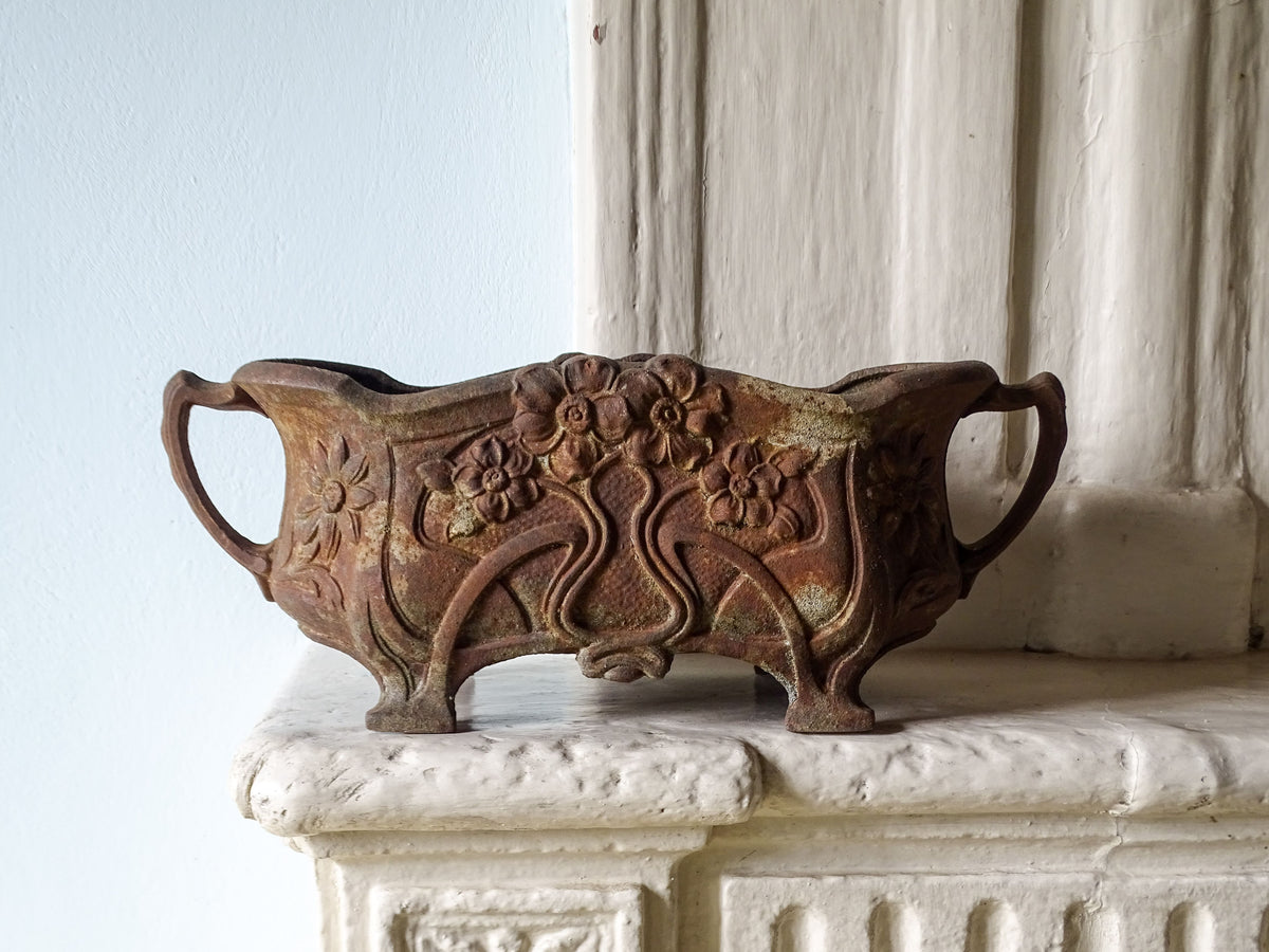 French antique cast iron art nouveau planter with floral decoration, displayed on a country house fireplace
