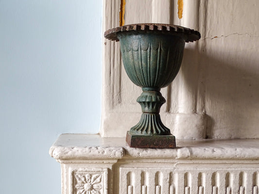 French antique cast iron garden urn with fluted bowl and pedestal base pictured on a country fireplace