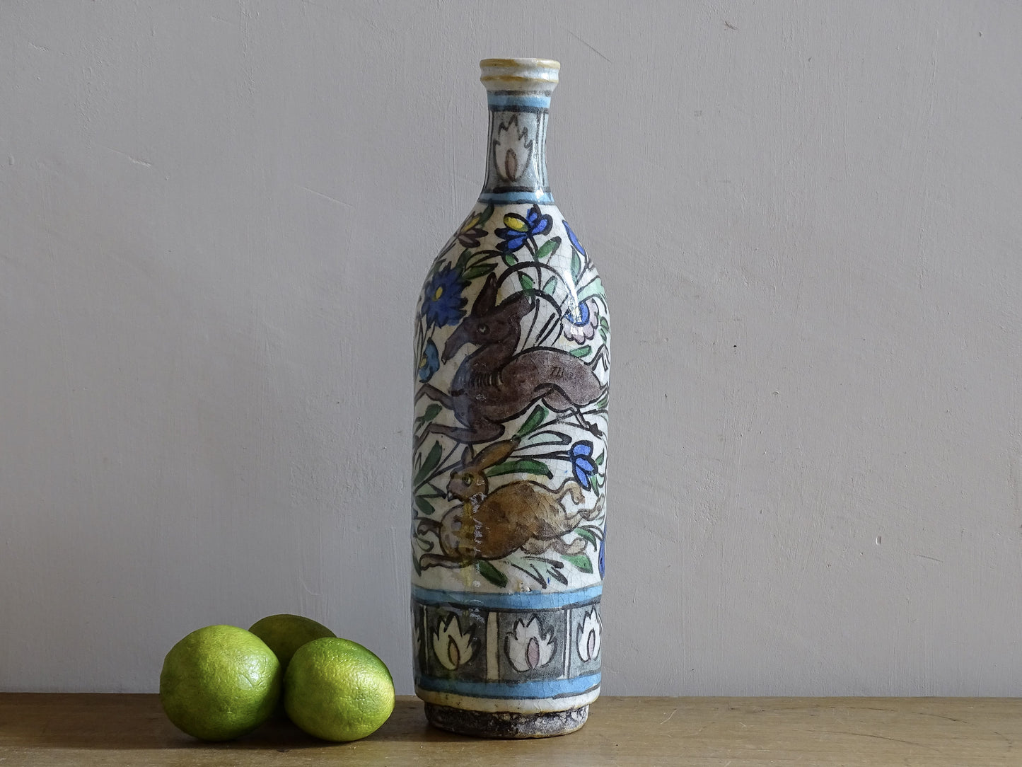 Antique pottery bottle in Iznik style with deer and rabbit among floral decoration.