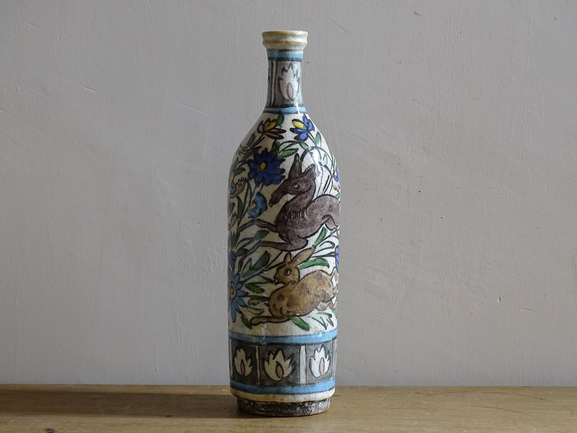 Antique Middle Eastern pottery bottle with cobalt blue and green decoration.