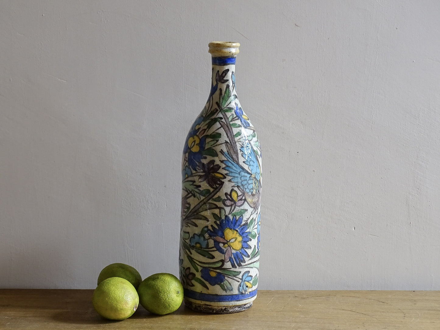 Tall antique pottery bottle in Iznik style with bird motifs.