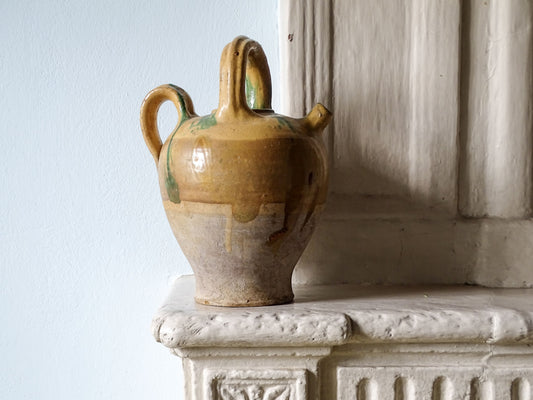 French antique pottery cruche with yellow glaze on a country house fireplace